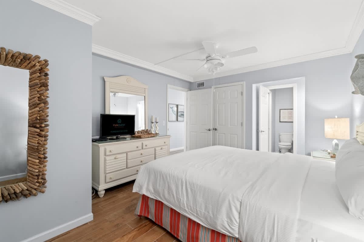 The Summit 502 – Bedroom with a king bed, dresser, mirror, TV, and access to a bathroom.