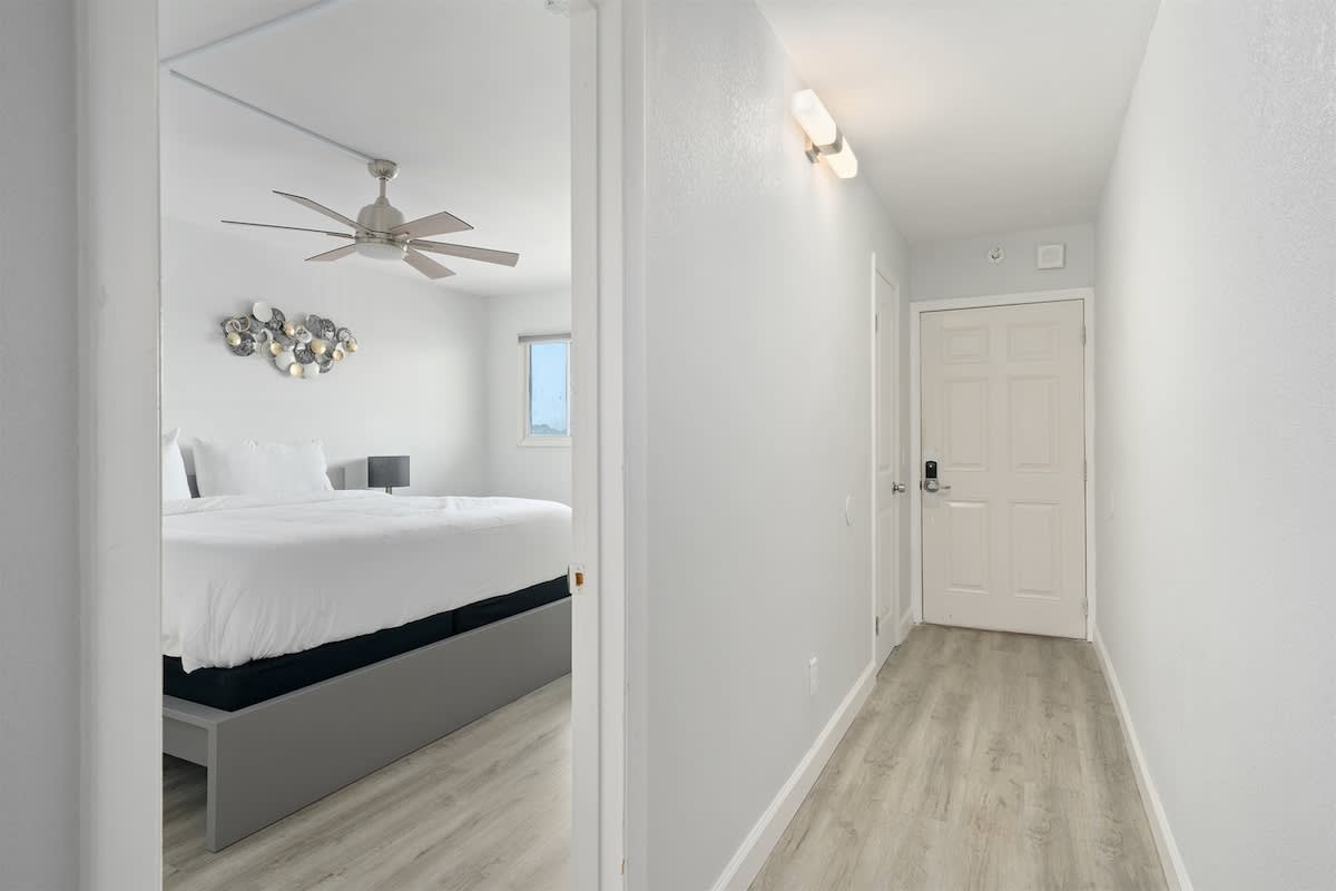 The Summit 626 – Hallway leading to a bedroom with a king-sized bed and window.