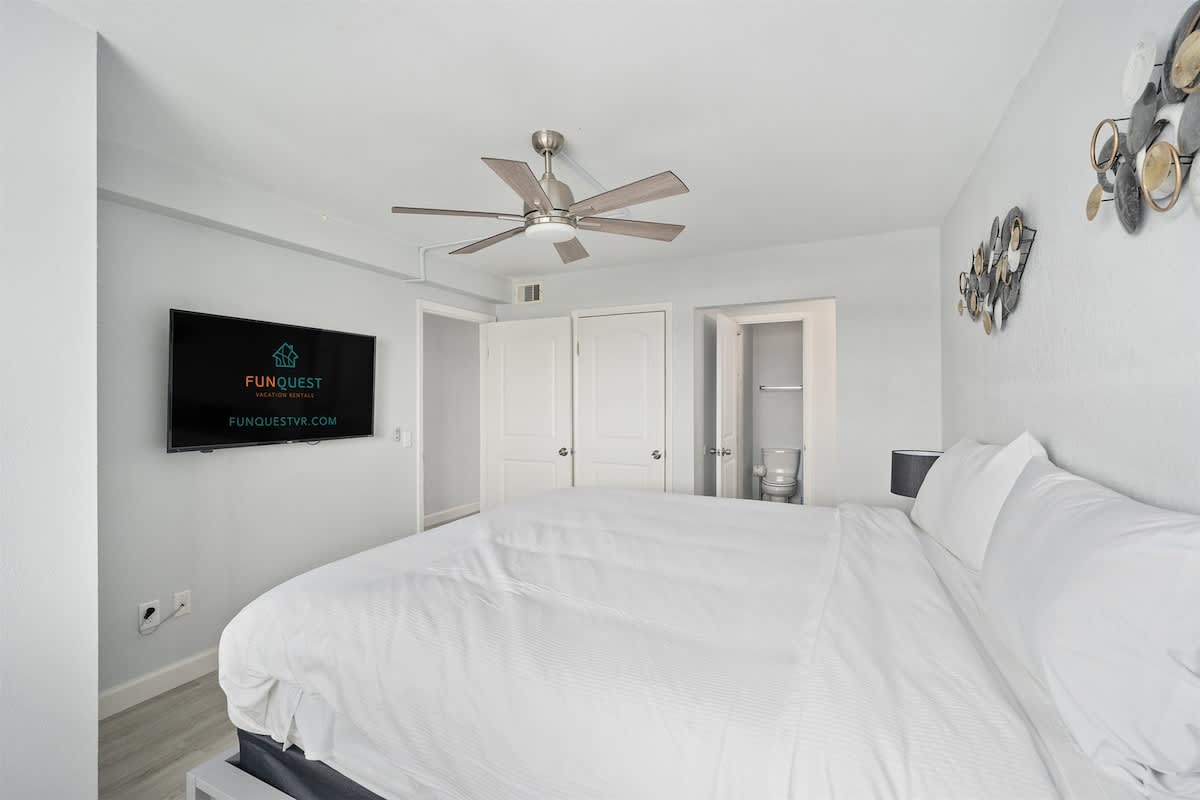 The Summit 626 – Bedroom with a king-size bed, ceiling fan, wall-mounted TV, and an adjoining bathroom.