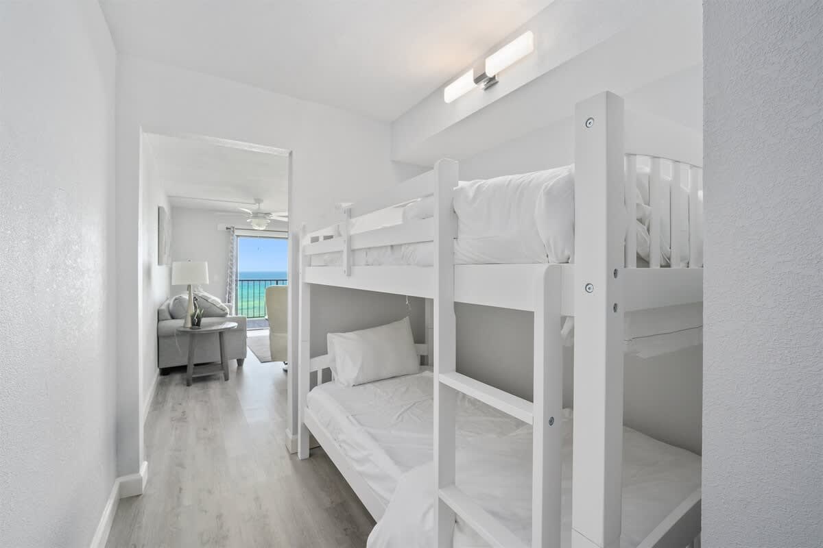 The Summit 626 – Bunk beds in a hallway with a view of the ocean beyond a living area.
