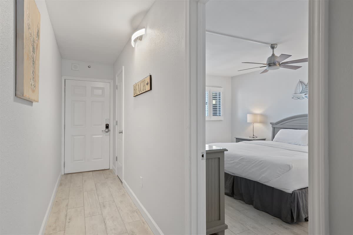 The Summit 615 – Hallway leading to a bedroom with a ceiling fan, double bed, and natural light from windows.