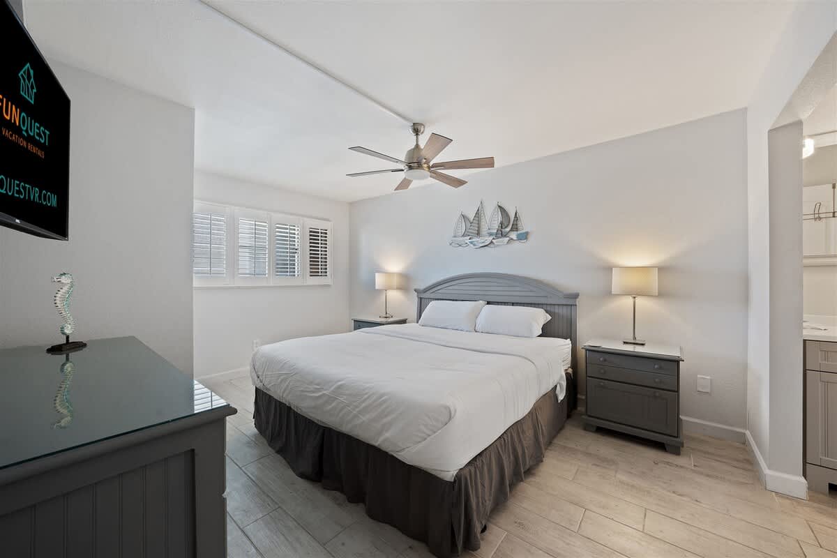 The Summit 615 – Cozy bedroom with a large bed, gray furniture, and ceiling fan, featuring shaded windows.