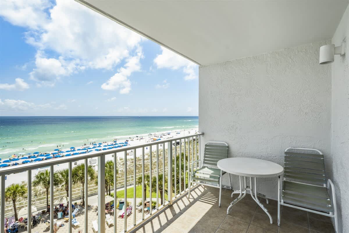 The Summit 613 – Balcony view with two chairs and a table overlooking beach and ocean.