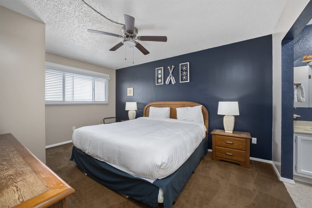 The Summit 613 – Cozy bedroom with a king-sized bed, nightstands, ceiling fan, and a bathroom visible in the background.