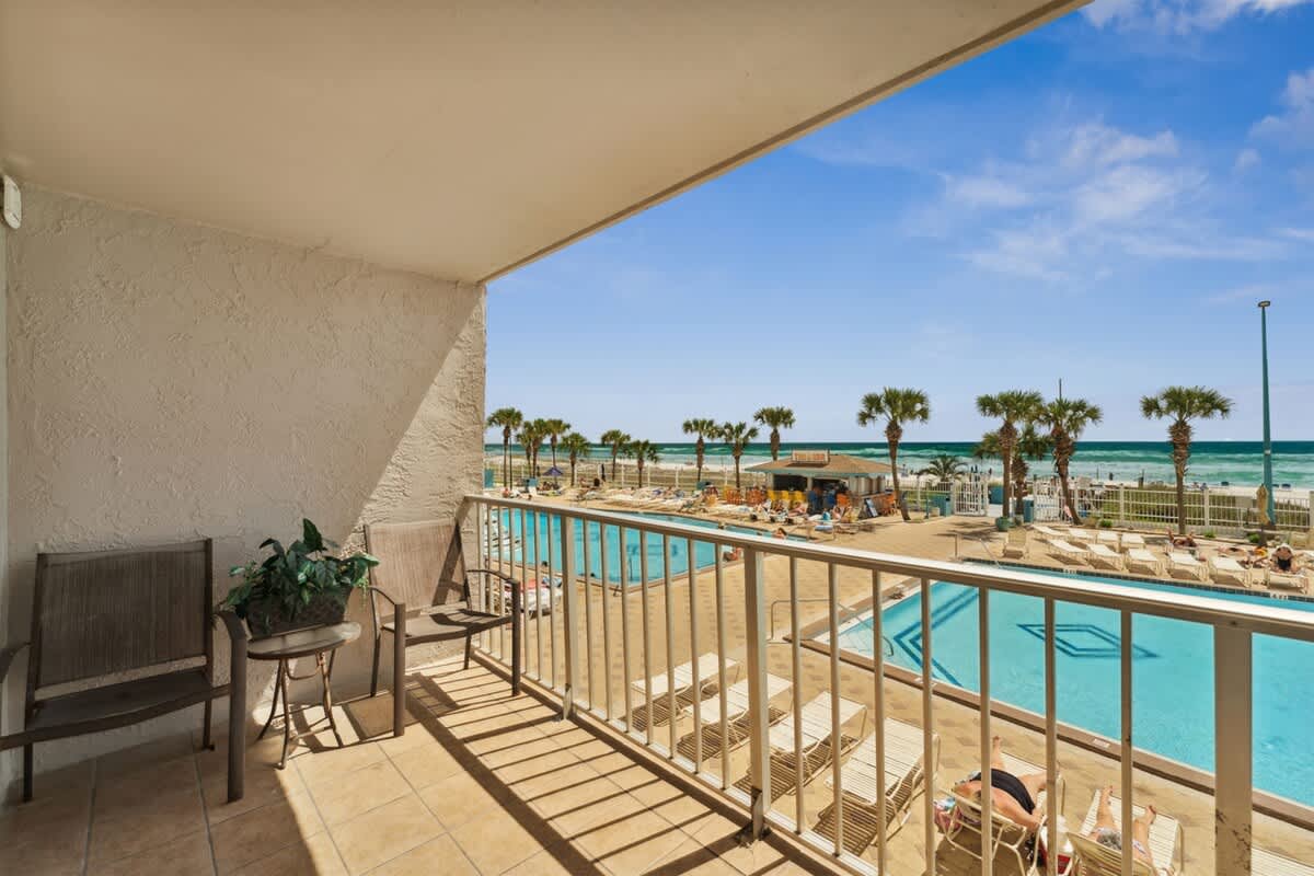 The Summit 215 – Balcony view of a pool area, beach, and ocean with palm trees.