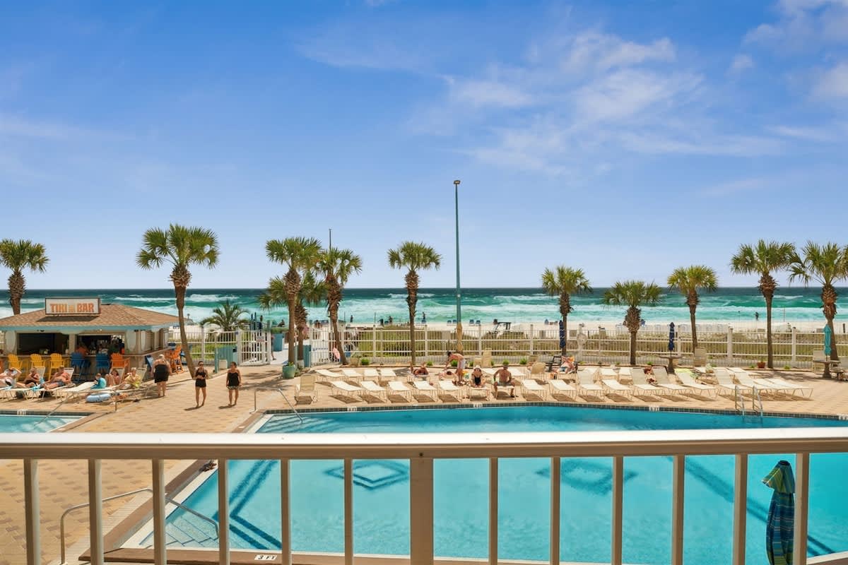 The Summit 215 – Pool area with beach view, palm trees, and a bar nearby.