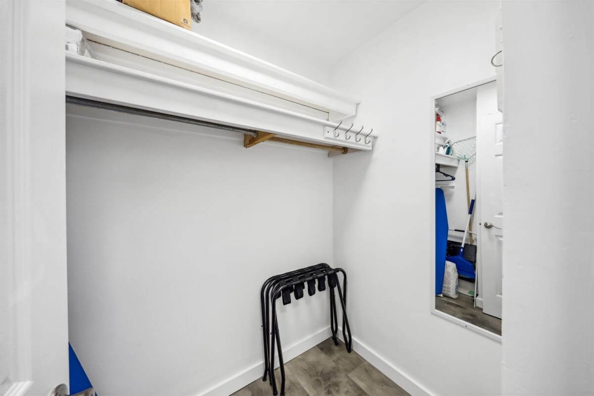 Top Of The Gulf 607 – Empty storage room with shelves, hooks, a mirror, and a folding chair rack.
