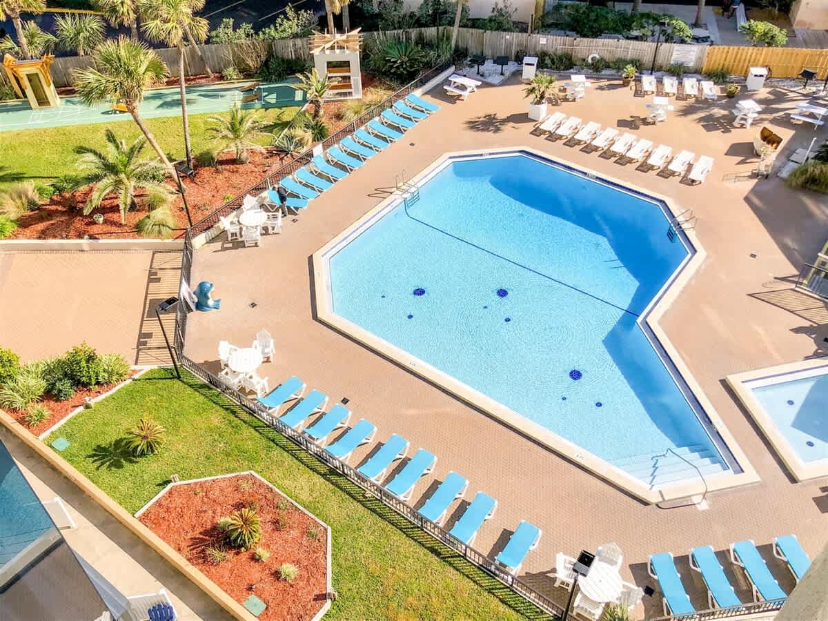 Top Of The Gulf 607 – View of a pool area with lounge chairs, palm trees, and landscaped grounds.