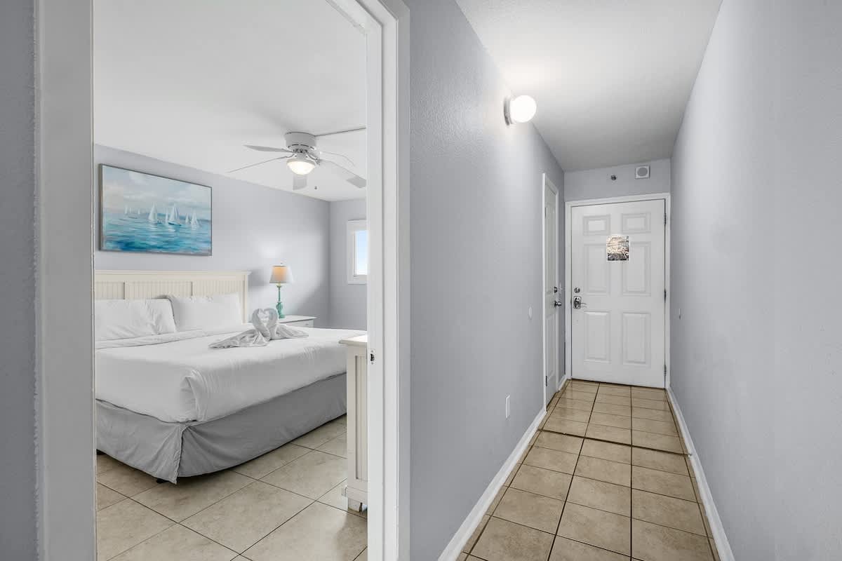 The Summit 606 – Hallway leading to a bedroom with a king bed, lamp, and art on the wall.