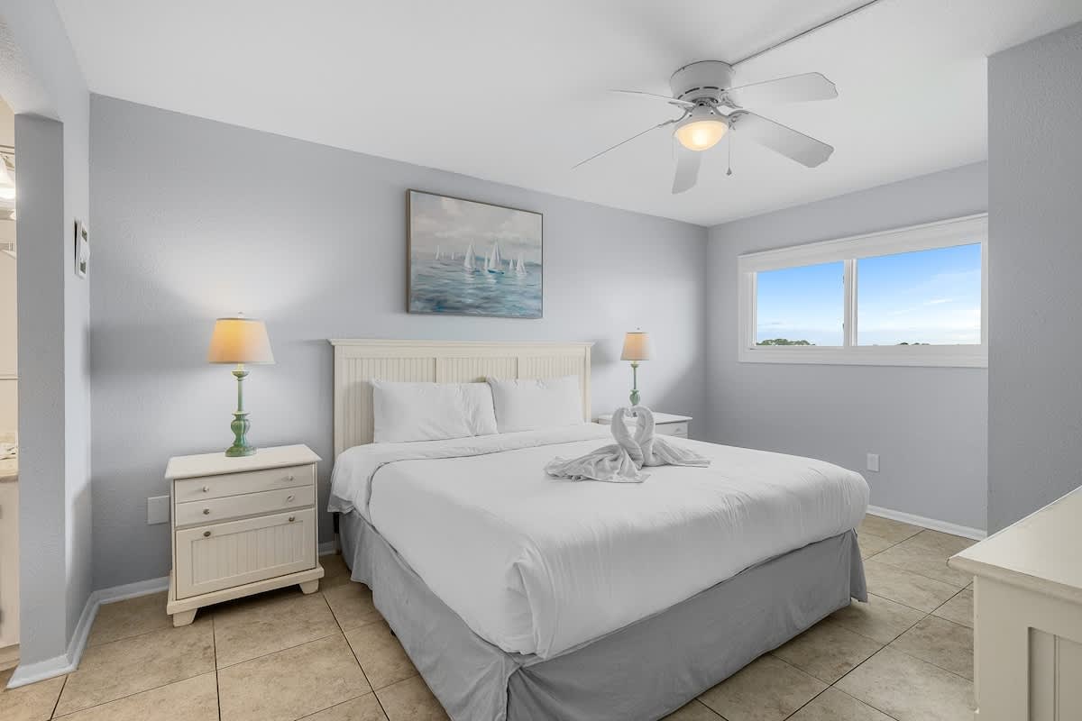 The Summit 606 – Cozy bedroom with a queen bed, ceiling fan, bedside lamps, and window view of the outdoors.