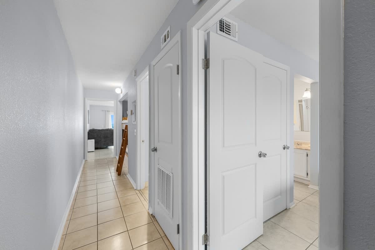The Summit 606 – Interior hallway leading to a living area and bathroom with tile flooring and light blue walls.