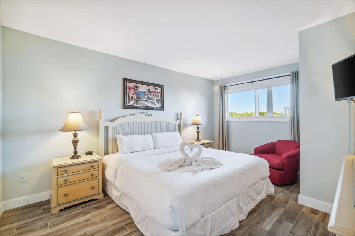 The Summit 108 – Bedroom with a queen bed, nightstand, lamp, armchair, window view, and decorative wall art.
