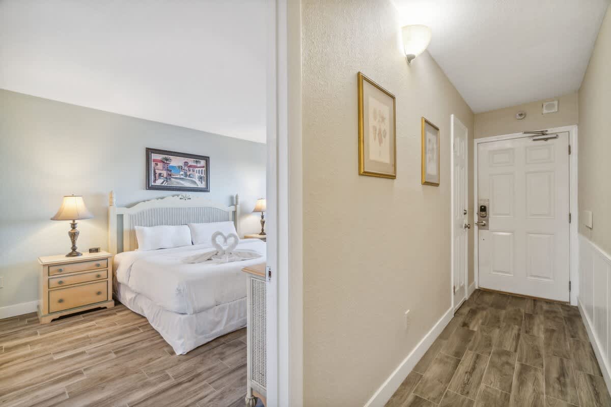 The Summit 108 – Hallway view leading to a bedroom with a king-size bed and two bedside lamps.
