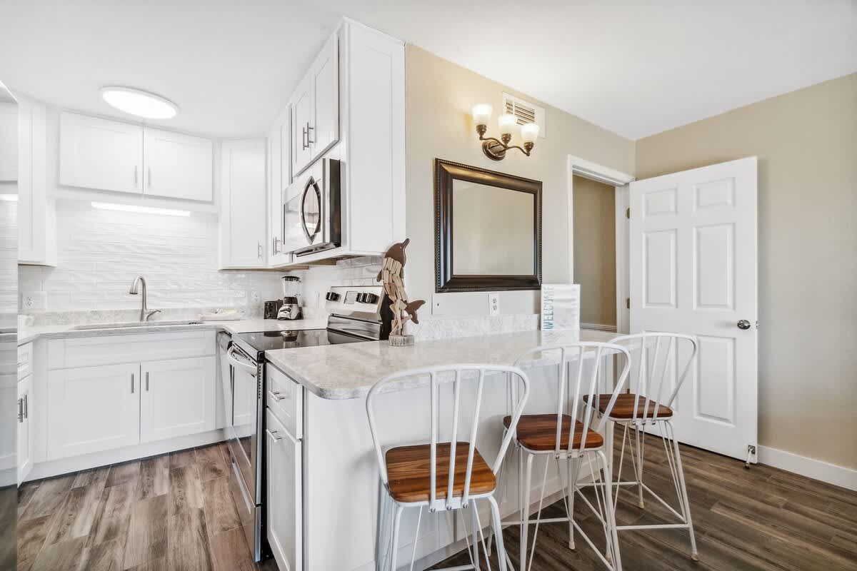 The Summit 108 – Modern kitchen with white cabinets, stainless steel appliances, and bar seating for four.