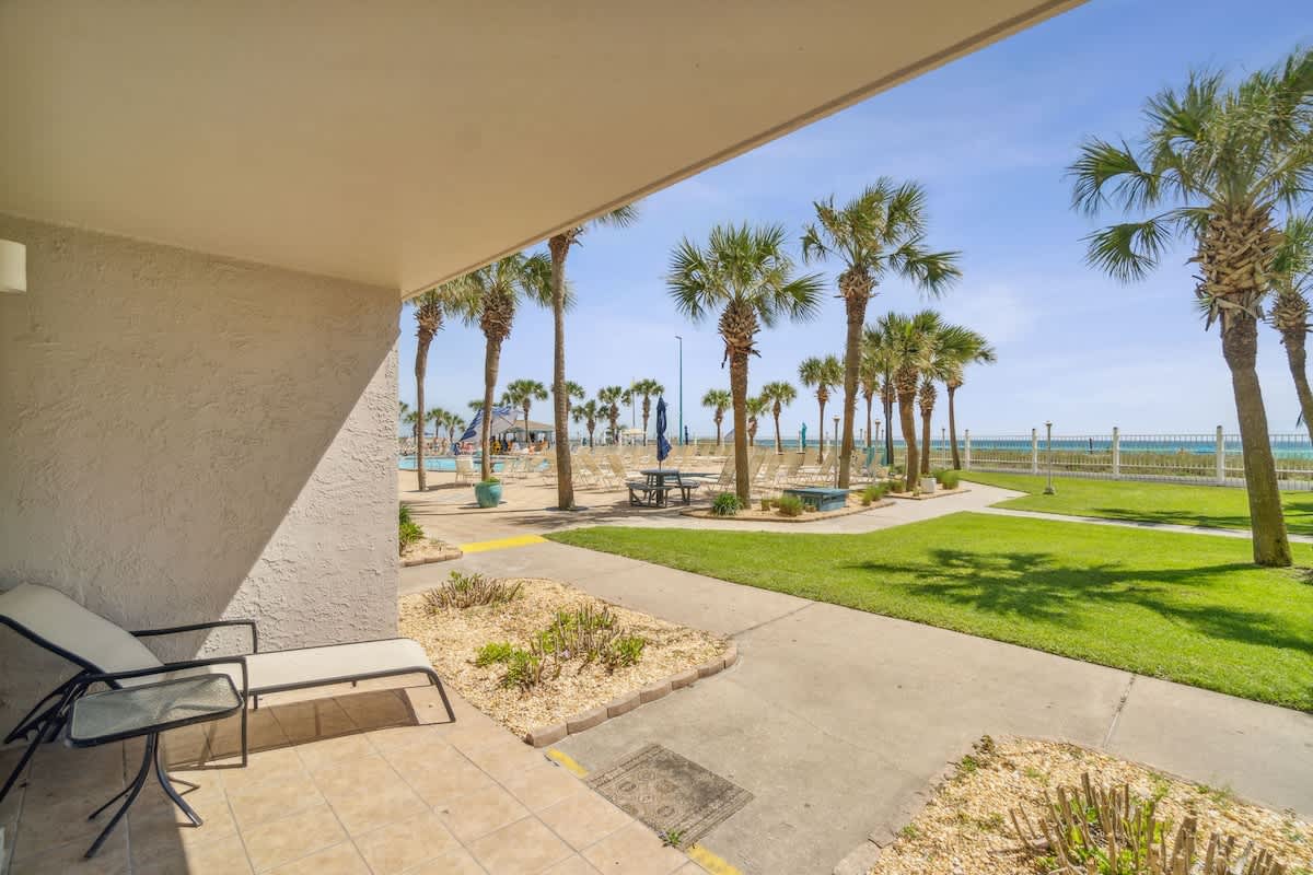 The Summit 108 – Patio view of palm trees, pool area, and beach from ground-level vacation rental.