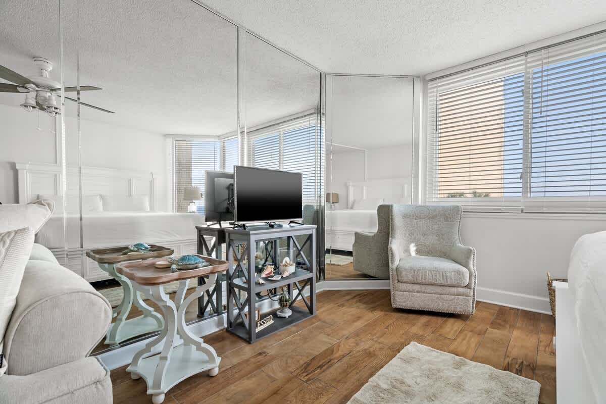 Top Of The Gulf 213 – Cozy bedroom with a king bed, TV, armchair, and large windows providing natural light.