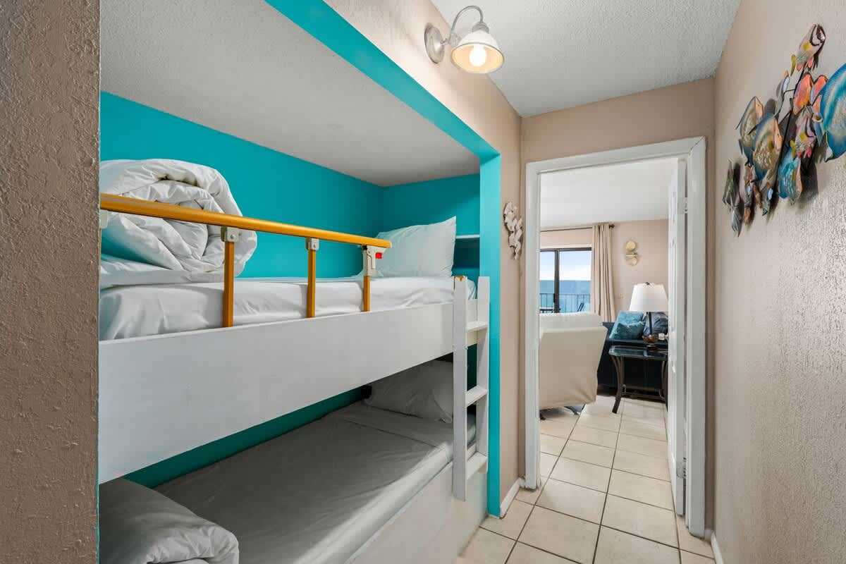 The Summit 1023 – Bunk beds in a hallway with turquoise accent wall and view of a living area beyond.