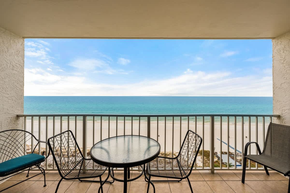The Summit 1023 – Balcony view overlooking the beach with a table and chairs.