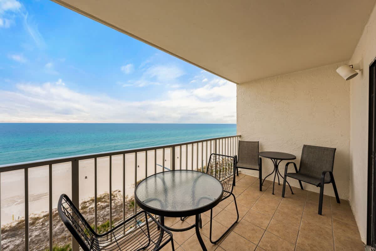 The Summit 1023 – Balcony with a glass table and chairs overlooking the beach and ocean view.