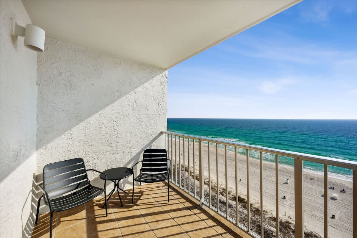 The Summit 1322 – Balcony with two chairs and a table overlooking the beach and ocean.