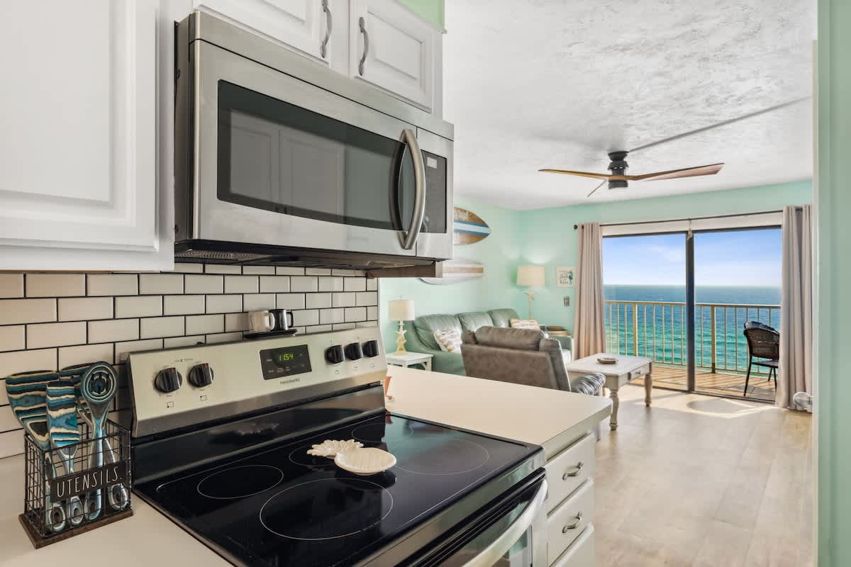 The Summit 1322 – Kitchen with stove and microwave, living area with ocean view and balcony.