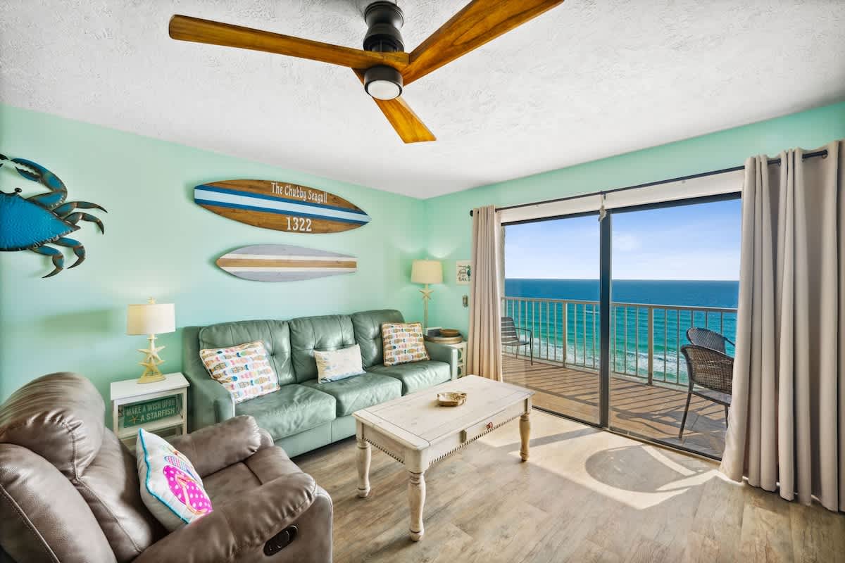The Summit 1322 – Living room with ocean view, green leather sofa, and wood coffee table.