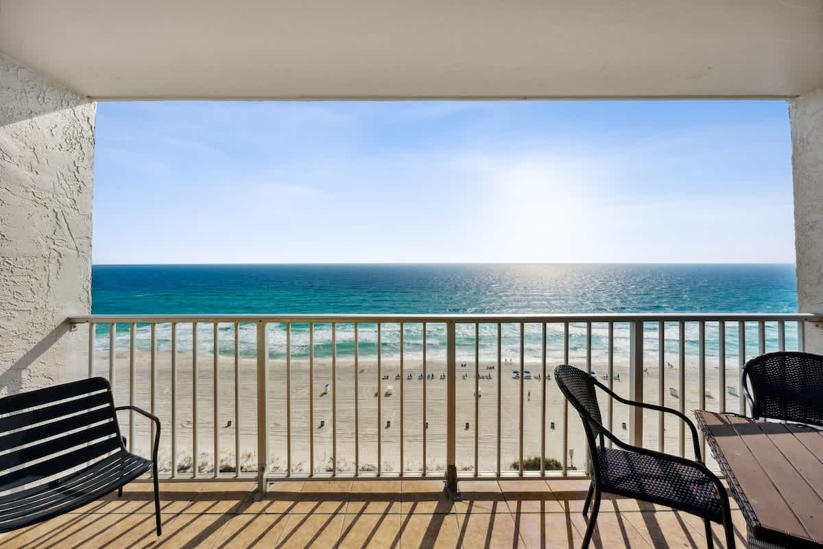 The Summit 1322 – Balcony view overlooking the beach and ocean, with black chairs and a table.