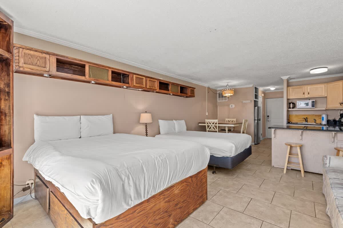 Top Of The Gulf 111 – Studio room with two queen beds, kitchen area, dining table, and a seating area.