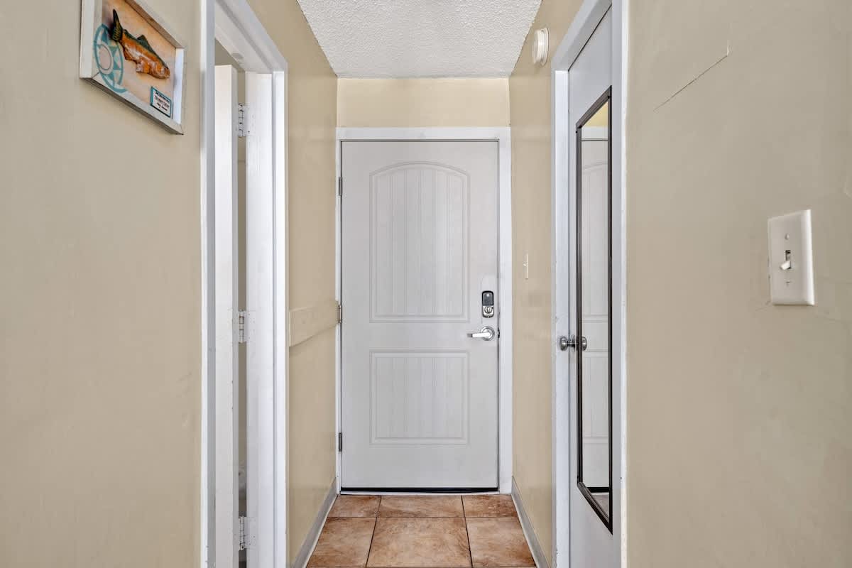 Top Of The Gulf 621 – Hallway entrance with beige walls, tiled floor, a mirror, and doors leading to rooms.