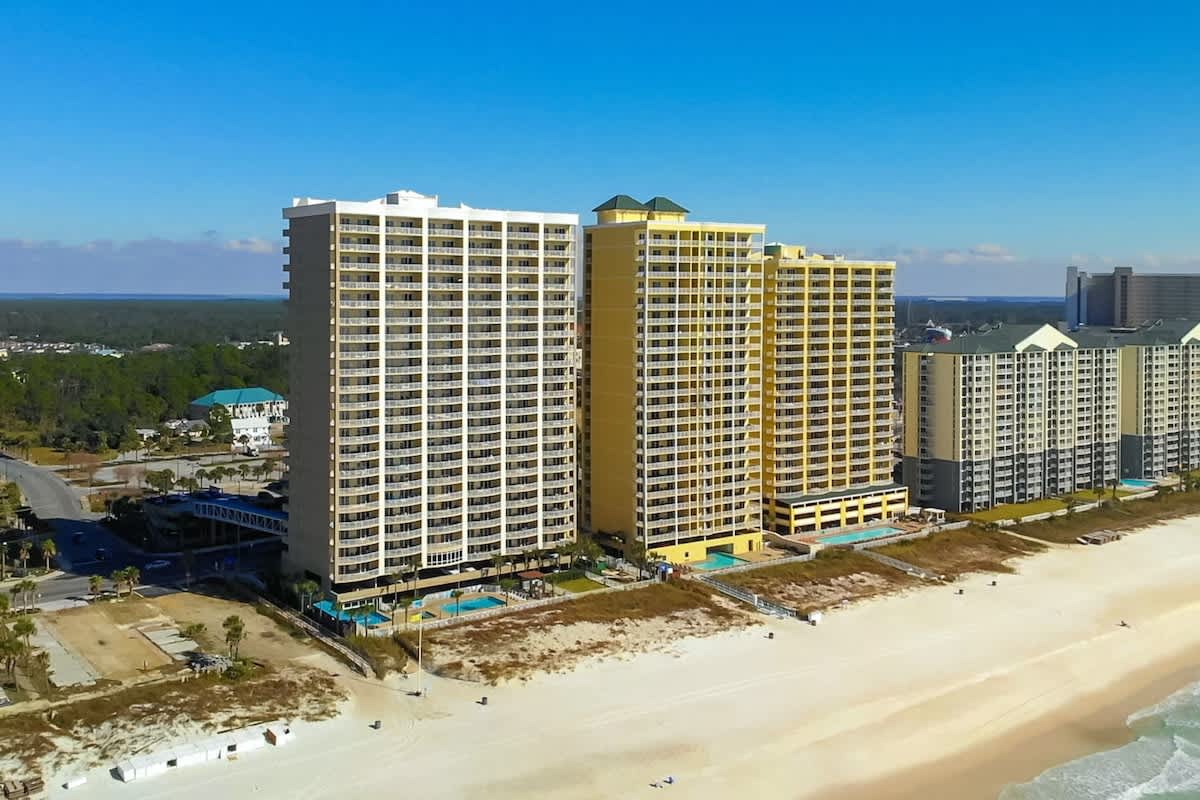 Ocean Villa 1302 – Aerial view of Ocean Villa 1302, two high-rise buildings near sandy beach and pools.