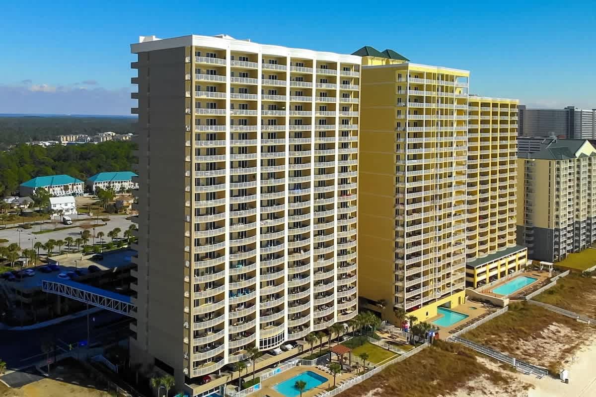 Ocean Villa 1302 – Aerial view of Ocean Villa 1302, beachfront building with multiple floors and pools below.