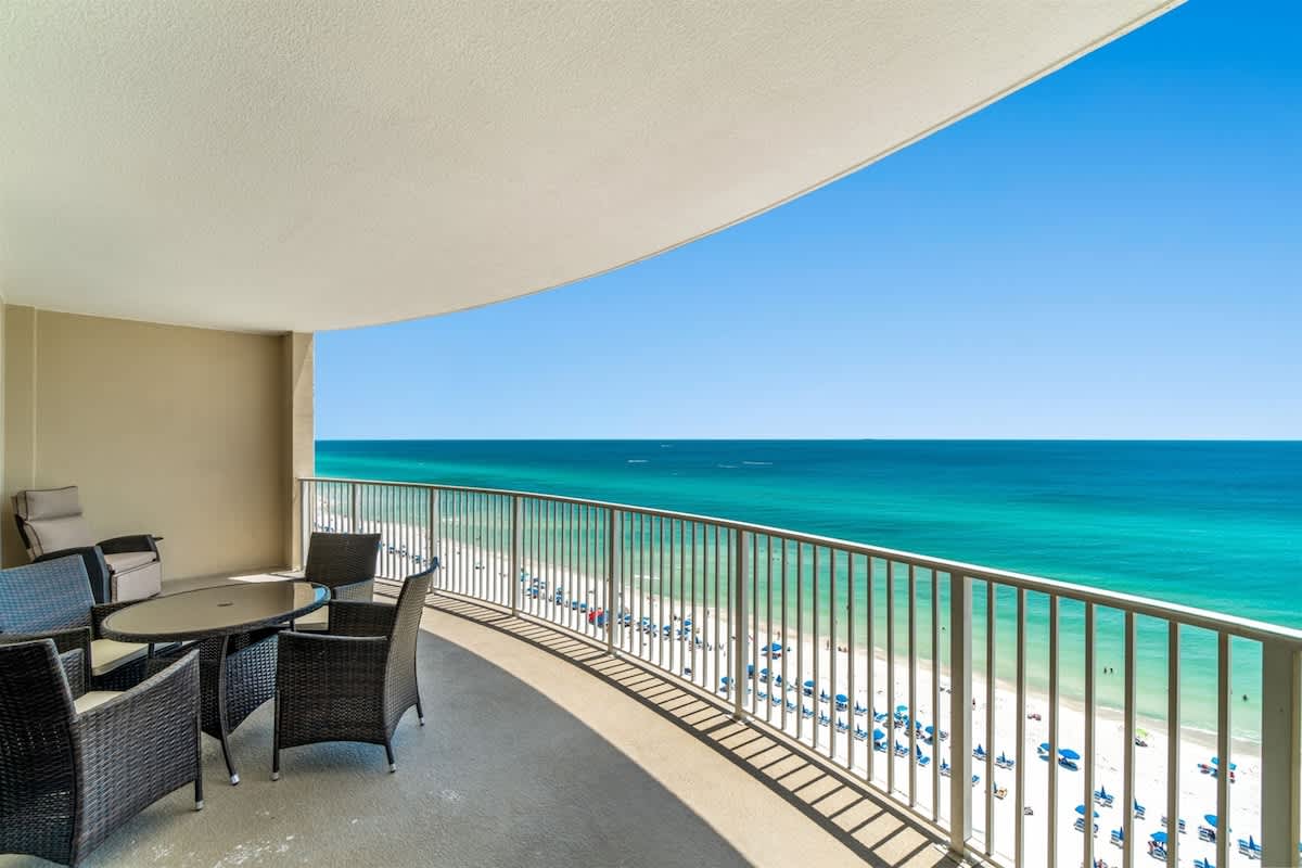 Ocean Villa 1302 – Balcony with a table and chairs overlooking the beach and turquoise ocean.