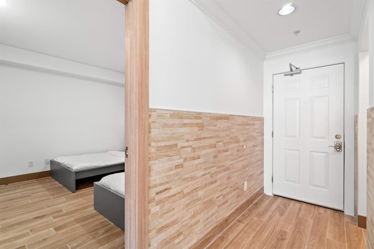 Ocean Villa 1302 – Entryway view with wooden flooring and a room containing two beds.