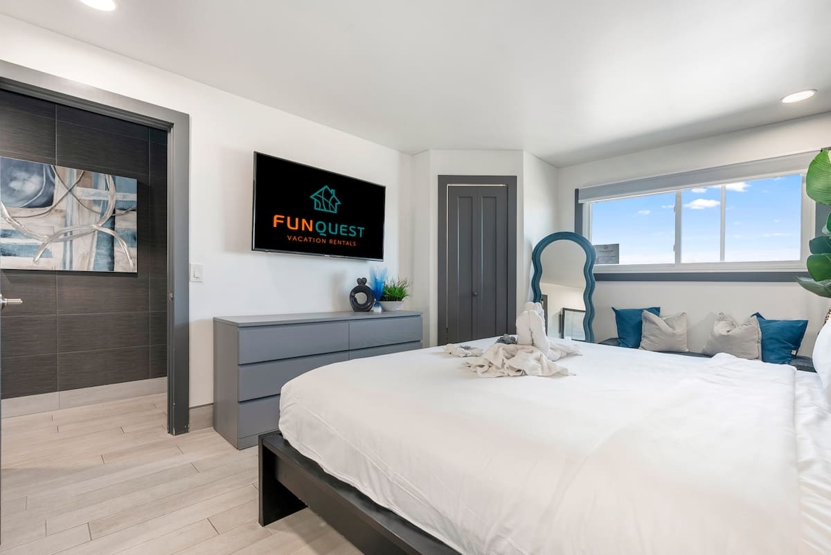The Summit 1205 – Modern bedroom with a king bed, dresser, TV, and window views.