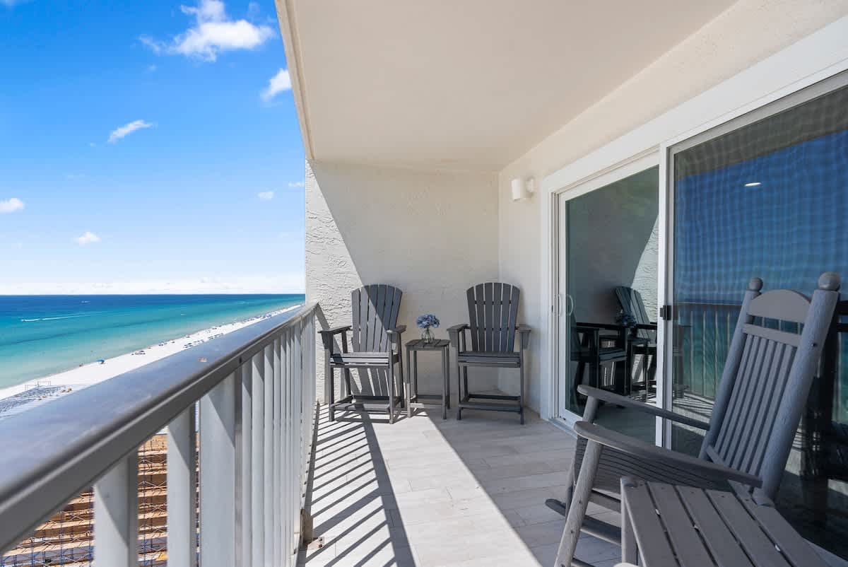 The Summit 1205 – Balcony with two rocking chairs, small table, and ocean view.