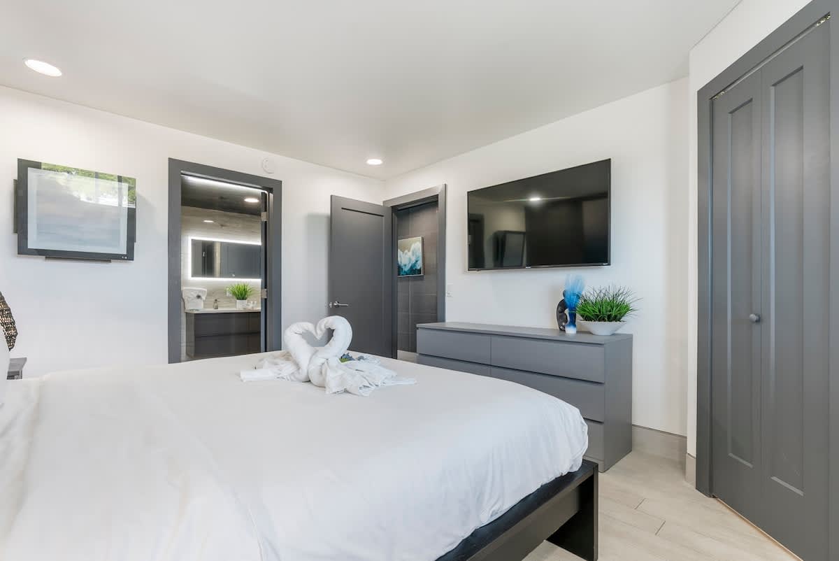 The Summit 1205 – Bedroom with a large bed, TV, dresser, and bathroom door. Decorative towels shaped like hearts.