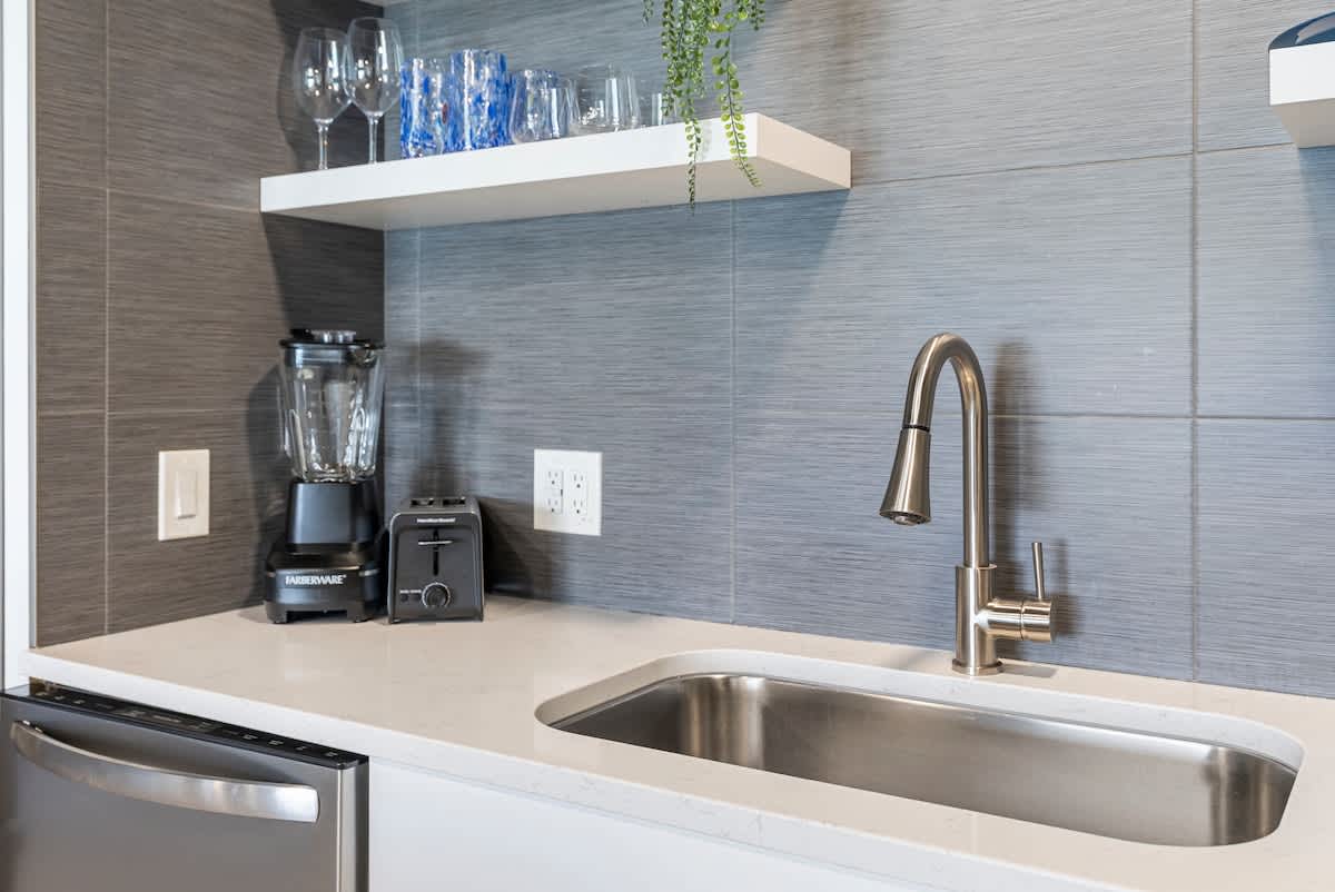 The Summit 1205 – Modern kitchen with stainless steel appliances, sink, blender, and toaster on countertop.