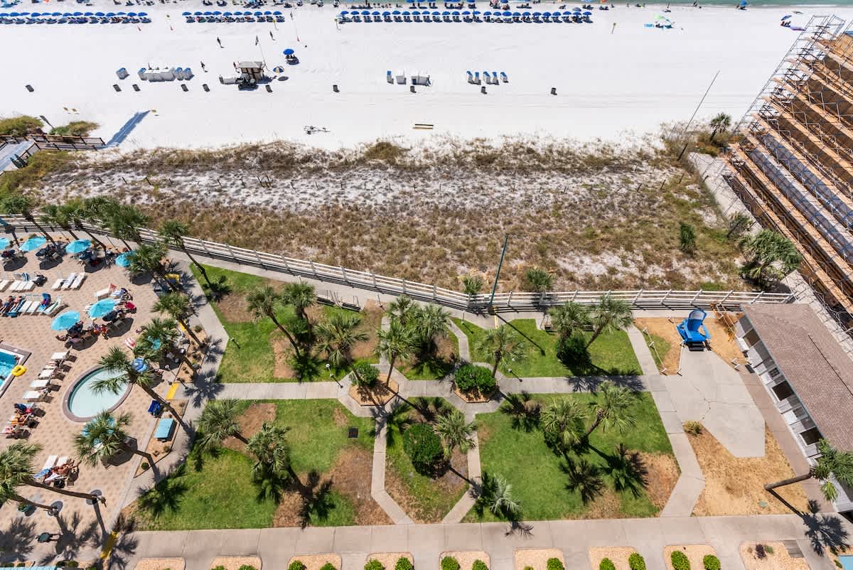 The Summit 1205 – Aerial view of pool area, gardens, and beach with lounge chairs in the background.