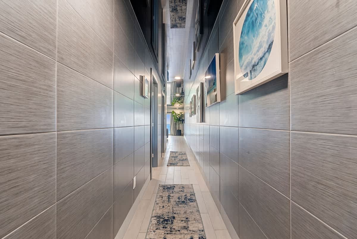 The Summit 1205 – Long hallway with modern decor, textured walls, and framed ocean photos.