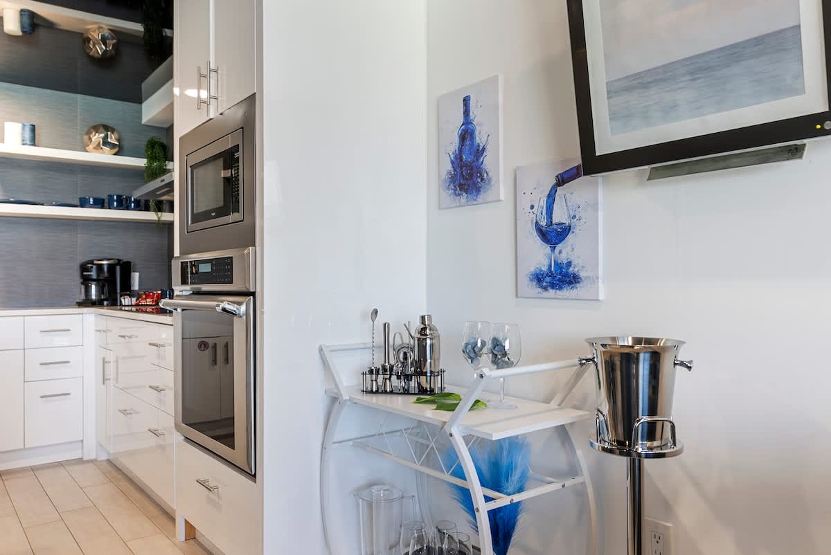 The Summit 1205 – Modern kitchen with stainless steel appliances, bar cart, and blue accent decor.