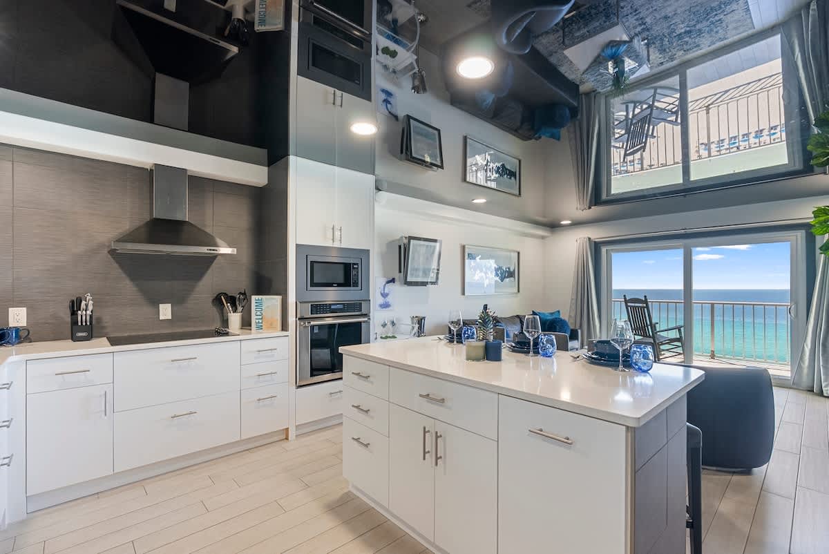 The Summit 1205 – Modern kitchen with white cabinets, ocean view, and dining area featuring a small table and seating.