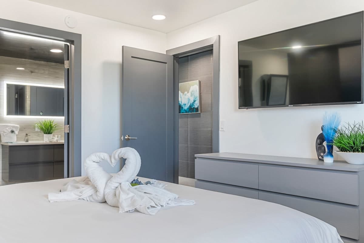 The Summit 1205 – Bedroom with a king bed, TV, and an en-suite bathroom visible through an open door.