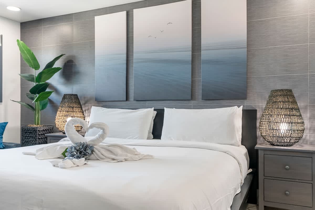 The Summit 1205 – Stylish bedroom with a king bed, decorative pillows, artwork, and tropical plant accents.