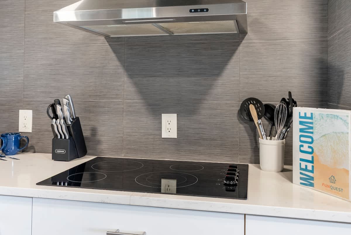 The Summit 1205 – Modern kitchen with an induction cooktop, knife block, utensils, and a welcome book on the countertop.