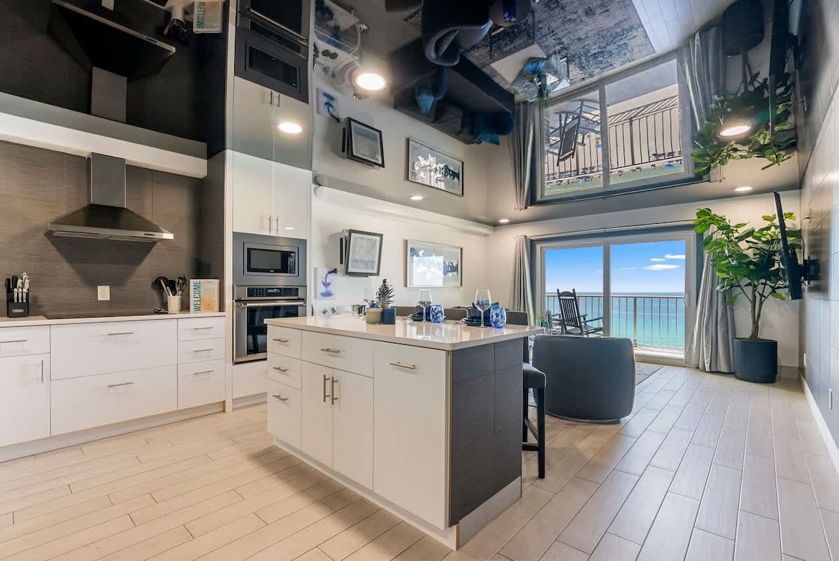 The Summit 1205 – Modern kitchen with island, ocean view, and seating area by balcony.