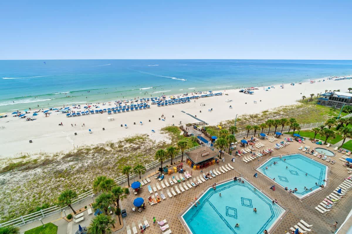 The Summit 1123 – View of beach, umbrellas, swimming pools, and palm trees from a high vantage point.