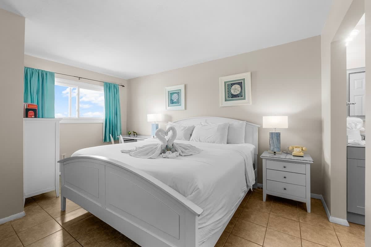The Summit 1123 – Bright bedroom with a queen bed, two nightstands, a window, and turquoise curtains.