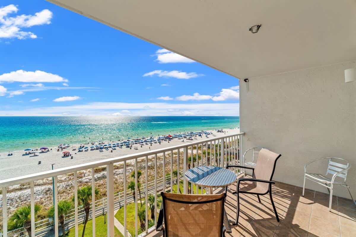 The Summit 731 – Balcony with two chairs and a table overlooking the beach and ocean.