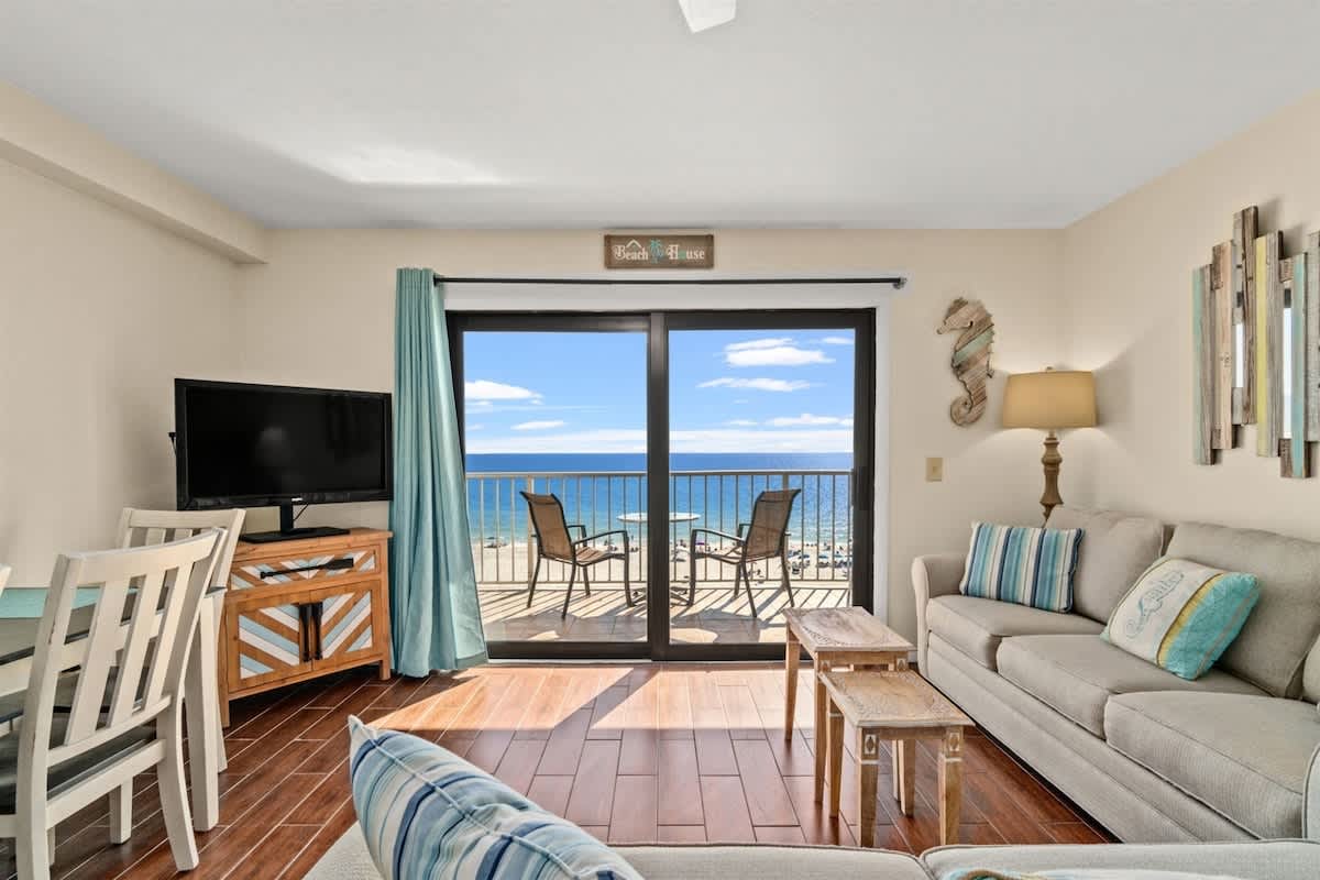 The Summit 731 – Living room with sofa, TV, and expansive ocean view through sliding glass doors.