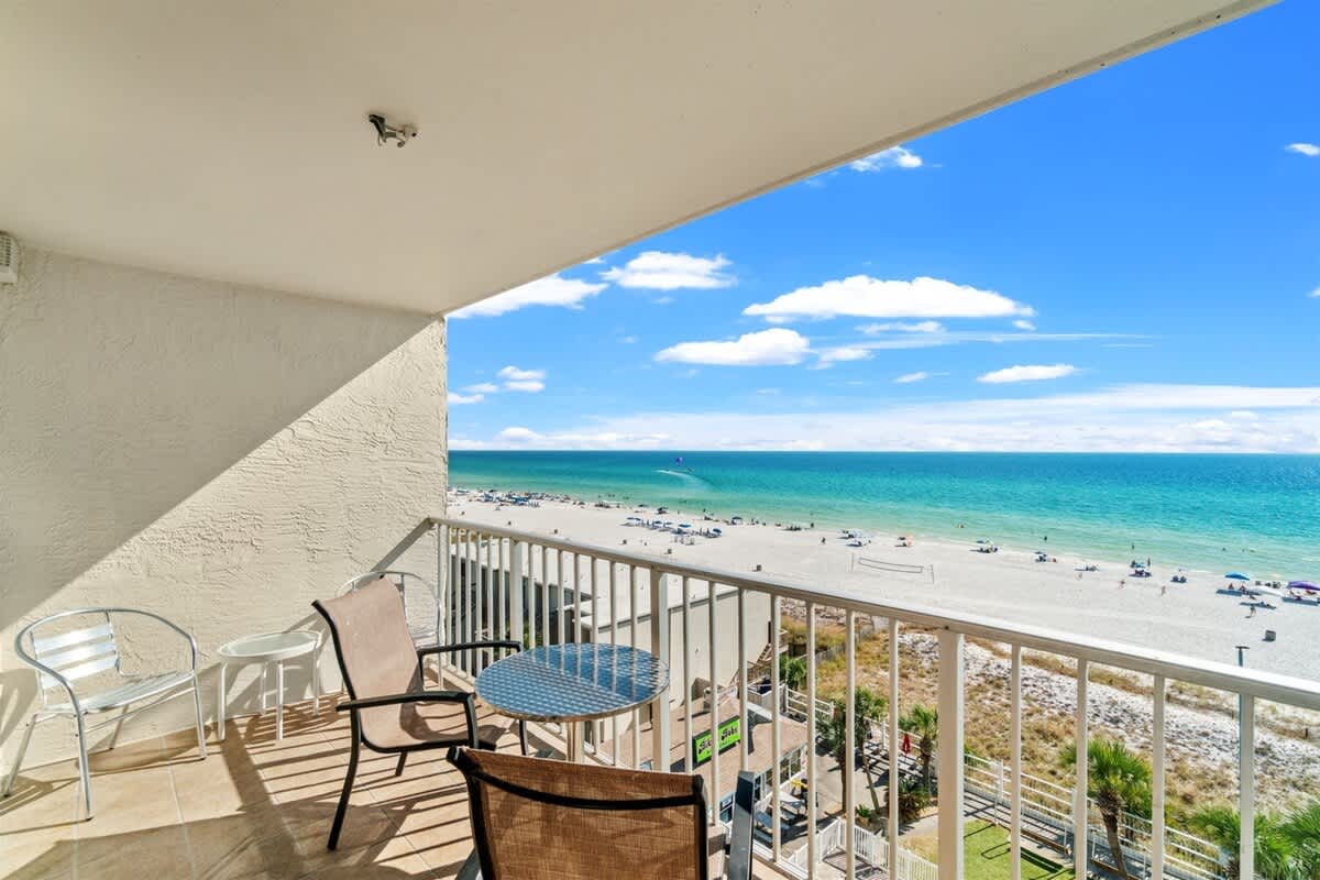 The Summit 731 – Balcony view from The Summit 731 overlooking the beach, with chairs and a table.